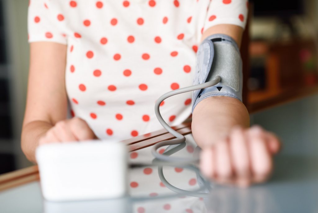 Woman measuring her own blood pressure at home