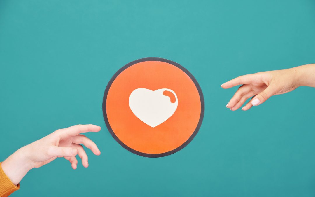 Hands of young man and woman reaching out for picture of heart in red circle