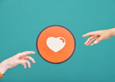 Hands of young man and woman reaching out for picture of heart in red circle